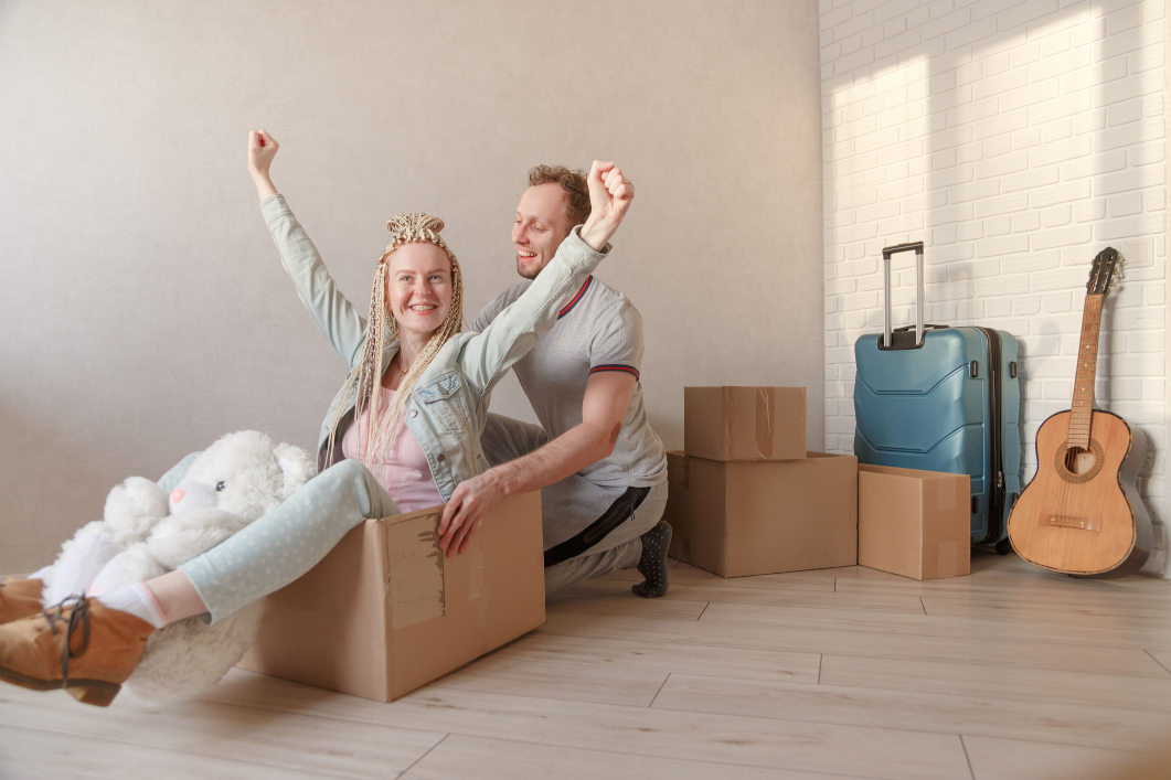 Couple in empty room with suitcase and guitar